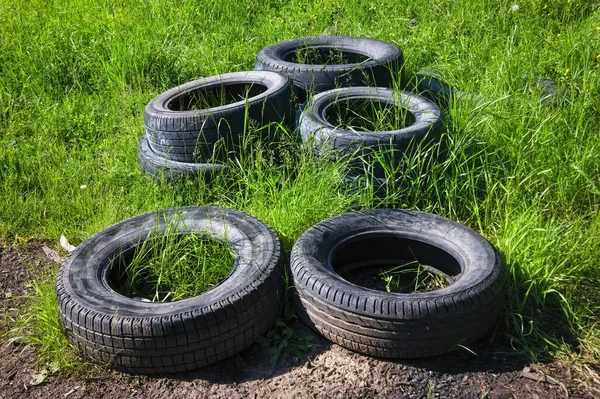 Dump of old used tires on fresh green grass in the forest. The problem of ecology and environmental pollution.