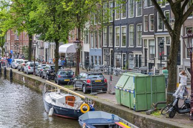 Amsterdam, Hollanda - 21 Ağustos 2019: Tipik Hollanda evleri ve tekneleriyle Lijnbaansgracht kanalının güzel manzarası. Amsterdam 'da 100 kilometreden fazla kanal ve 1500 köprü var..