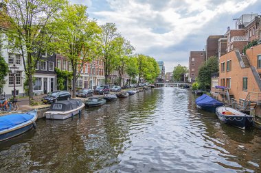 Amsterdam, Hollanda - 21 Ağustos 2019: Tipik Hollanda evleri ve tekneleriyle Lijnbaansgracht kanalının güzel manzarası. Amsterdam 'da 100 kilometreden fazla kanal ve 1500 köprü var..