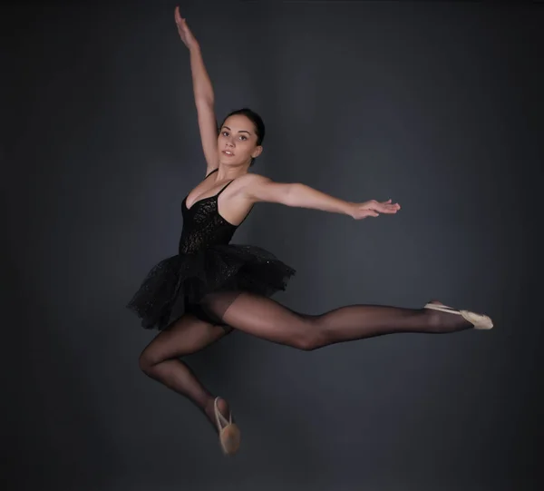 Ballerina in black outfit posing in studio.