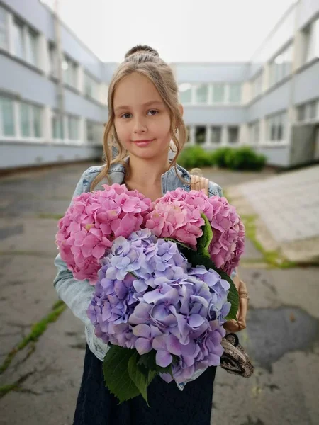 little girl with hydrangea flowers near school