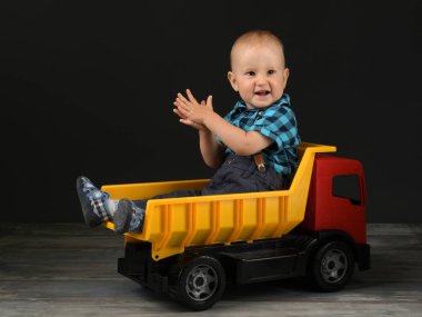 Küçük çocuk büyük oyuncak kamyonla oynuyor.