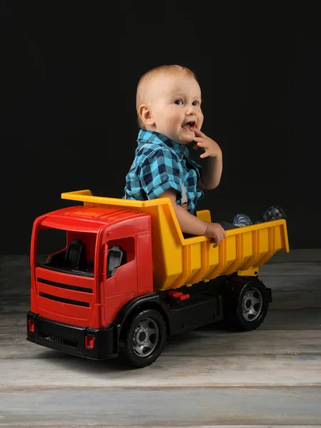 little boy plays with big toy truck