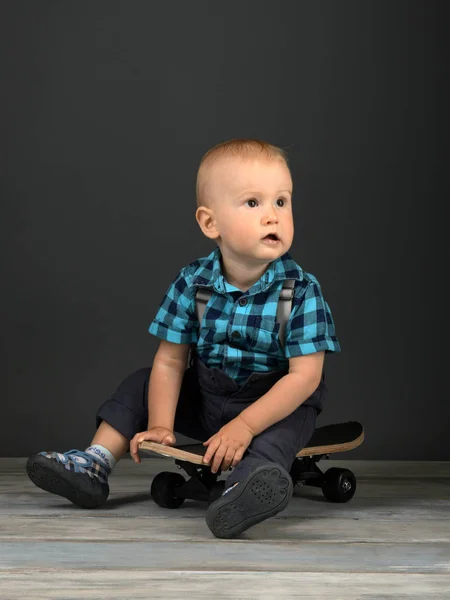 小さな男の子がスタジオでスケートボードに座って — ストック写真