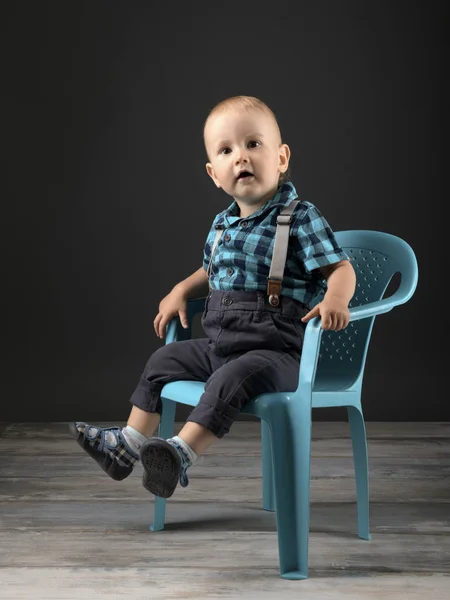 小さな男の子がスタジオのプラスチック製の椅子に座り — ストック写真