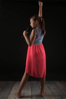 Küçük kız stüdyoda mikrofonla şarkı söylüyor.