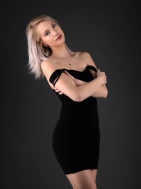 Şık siyah elbiseli, sarı saçlı ve parlak makyajlı muhteşem şehvetli bir kadının moda stüdyosu fotoğrafı.