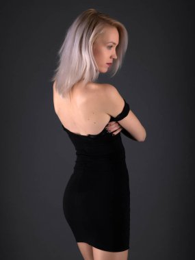 Şık siyah elbiseli, sarı saçlı ve parlak makyajlı muhteşem şehvetli bir kadının moda stüdyosu fotoğrafı.