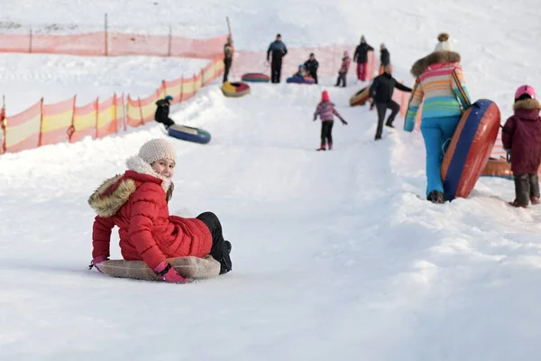 快乐的小女孩在雪地的公园里滑下山去 — 图库照片