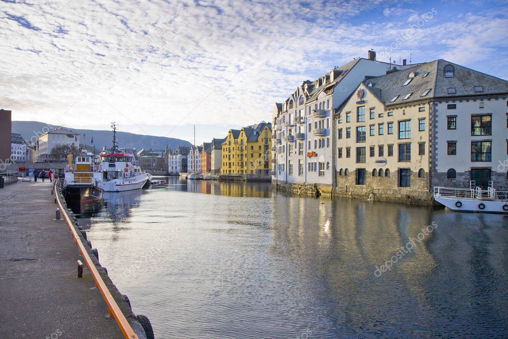 Small boats and old sailing ship at Alesund old town houses background. Norway.