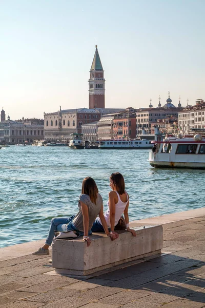 Venice, İtalya - 25 Eylül 2016: İki kız bankta oturan ve Venedik'in izlerken