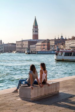 Venice, İtalya - 25 Eylül 2016: İki kız bankta oturan ve Venedik'in izlerken