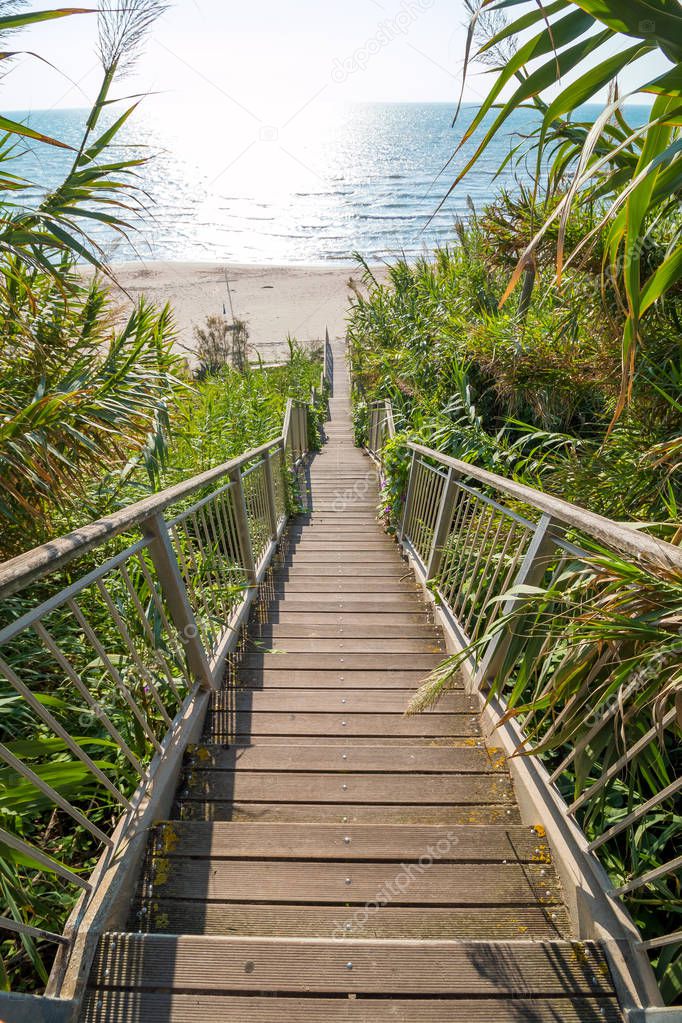 Wooden stairs leading off the cliff onto the sand on a sunny day, Wooden board walk stairs