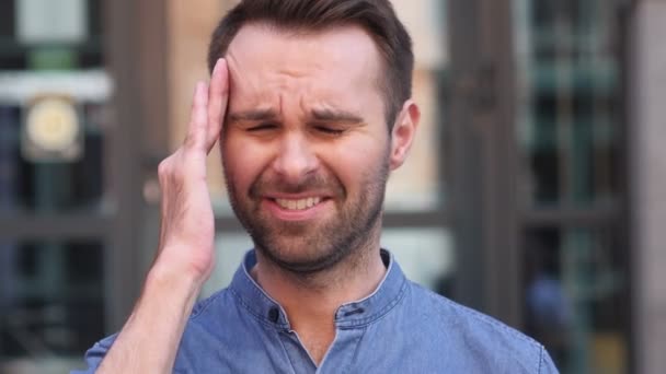 Gespannen Casual Man met hoofdpijn staande buitenkant gebouw — Stockvideo