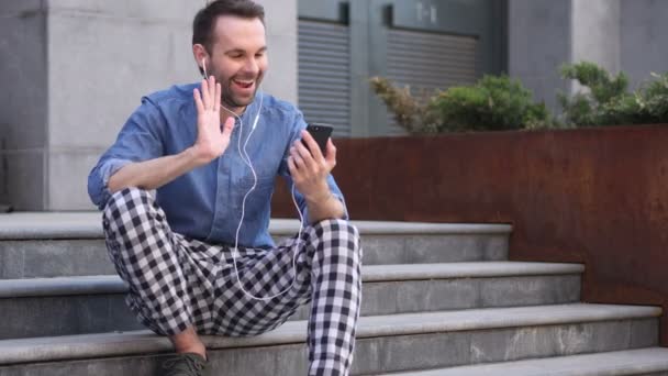 Chat de vídeo en línea por el hombre casual sentado en las escaleras — Vídeos de Stock