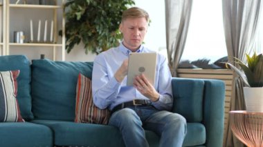 Tablet PC'de orta yaşlı adam oturarak alışveriş online