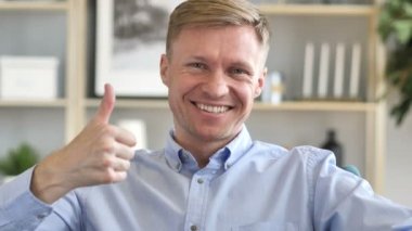 Başparmak yukarıya kameraya bakarak, iş yerinde iş adamı tarafından