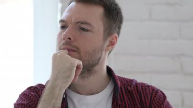 Düşünme ve dizüstü bilgisayarda çalışan dalgın genç adam