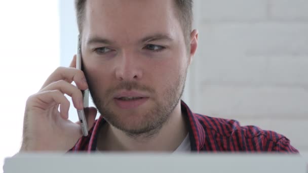 Hombre Joven Hablando Por Teléfono Mientras Trabaja Ordenador Portátil — Vídeos de Stock