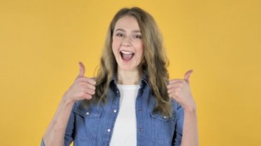 Genç güzel kız sarı zemin üzerine başparmak el hareketi