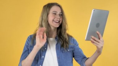 Genç güzel kız sarı zemin üzerine Tablet ile tarafından görüntülü sohbet