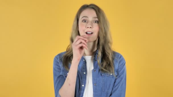 思考若いきれいな女の子は黄色の背景に新しいアイディアを得た — ストック動画