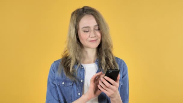 Joven Chica Bonita Navegando Smartphone Sobre Fondo Amarillo — Vídeos de Stock