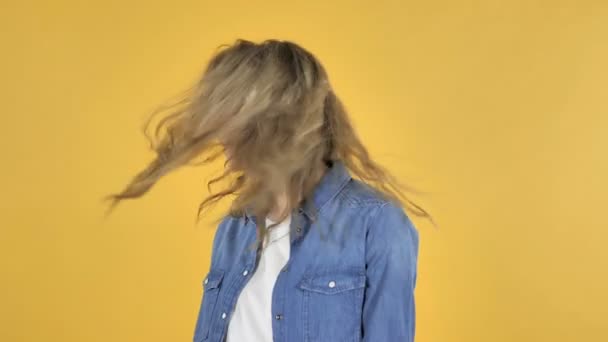 若い可愛い女の子が黄色の背景上分離彼女の頭の揺れ — ストック動画
