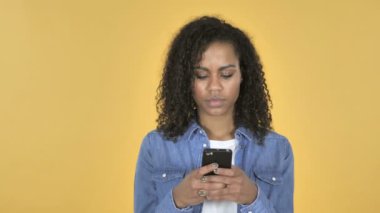 Afrikalı kız sarı arka plan üzerinde izole Smartphone tarama