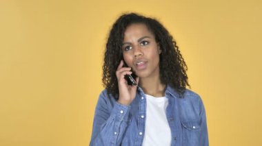 Afrikalı kız sarı arka plan üzerinde izole Smartphone cep telefonu ile konuşmak