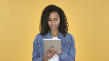 Afrikalı kız heyecanlı başarı kullanarak Tablet izole sarı arka plan üzerinde süre için