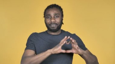 El yapımı kalp üzerinde sarı arka plan izole rahat Afrika adam tarafından