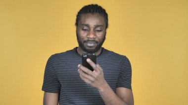 Casual Afrika adam akıllı telefon üzerinde sarı arka plan izole tarama