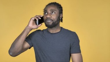 Sarı arka plan üzerinde izole Smartphone cep telefonu ile konuşurken rahat Afrika adam