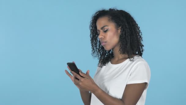 Африканская Девушка Шоке Использовании Смартфона Изолированы Синем Фоне — стоковое видео