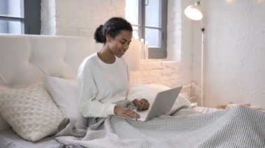 Laptop genç Afrikalı kız yatakta oturmuş tarafından online görüntülü sohbet