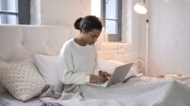 Şok genç Afrikalı kız yatakta laptop sonuçları için merak