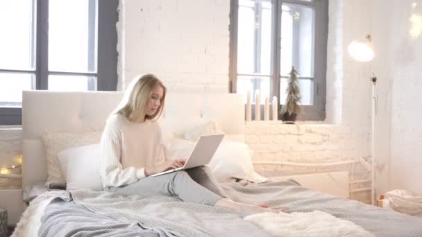 カジュアルな若い女の子のベッドに座って ノート パソコンで入力 — ストック動画