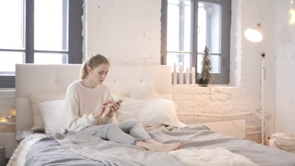 Ung Flicka Med Smartphone Medan Sitter Sängen — Stockvideo