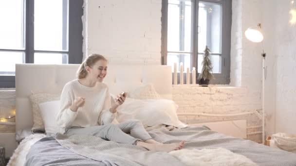 Opgewekt Meisje Zit Bed Vieren Van Succes Smartphone — Stockvideo