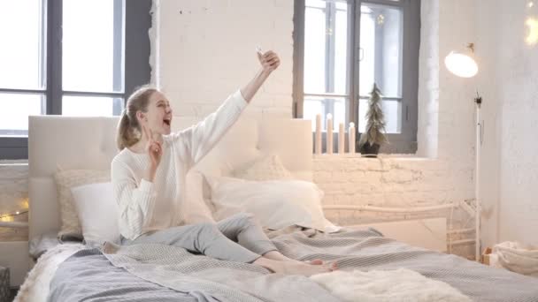 Glückliches Mädchen Das Bett Sitzt Und Seflie Mit Dem Handy — Stockvideo