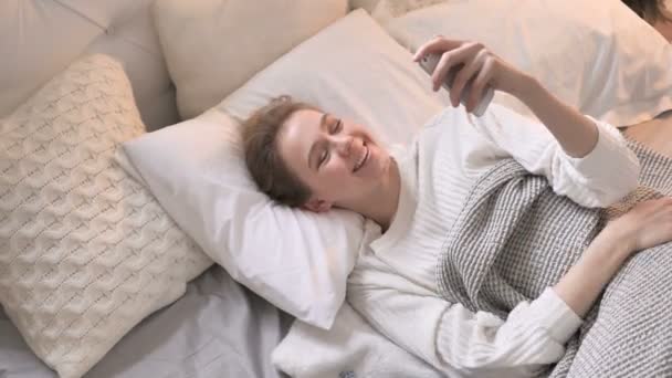 在床上躺在床上的年轻女孩在线视频聊天的顶观 — 图库视频影像