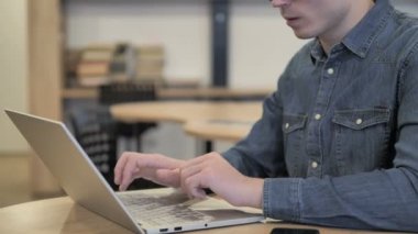 Düşünme ve dizüstü bilgisayarda çalışan dalgın yaratıcı genç adam