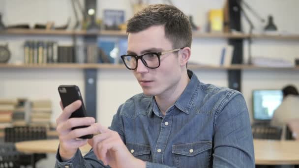 Kreativer Mann mit Brille reagiert auf Verlust im Smartphone