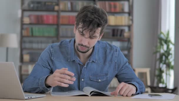 Junger Mann Liest Magazin Buch Lockeren Büro — Stockvideo