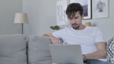 Rahatlatıcı genç adam düşünme fikir ve çalışma üstünde Laptop