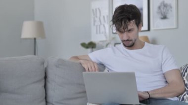Online Video sohbet etmek üstünde Laptop rahatlatıcı genç adam tarafından