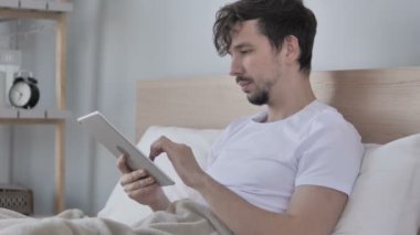 Genç adam kullanarak Tablet Lying yatakta iken