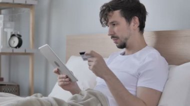 Tablet yatakta genç adam tarafından online alışveriş
