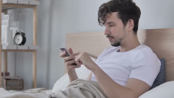 Uomo Utilizzando Smartphone Mentre Sdraiato Sul Fianco Letto — Video Stock